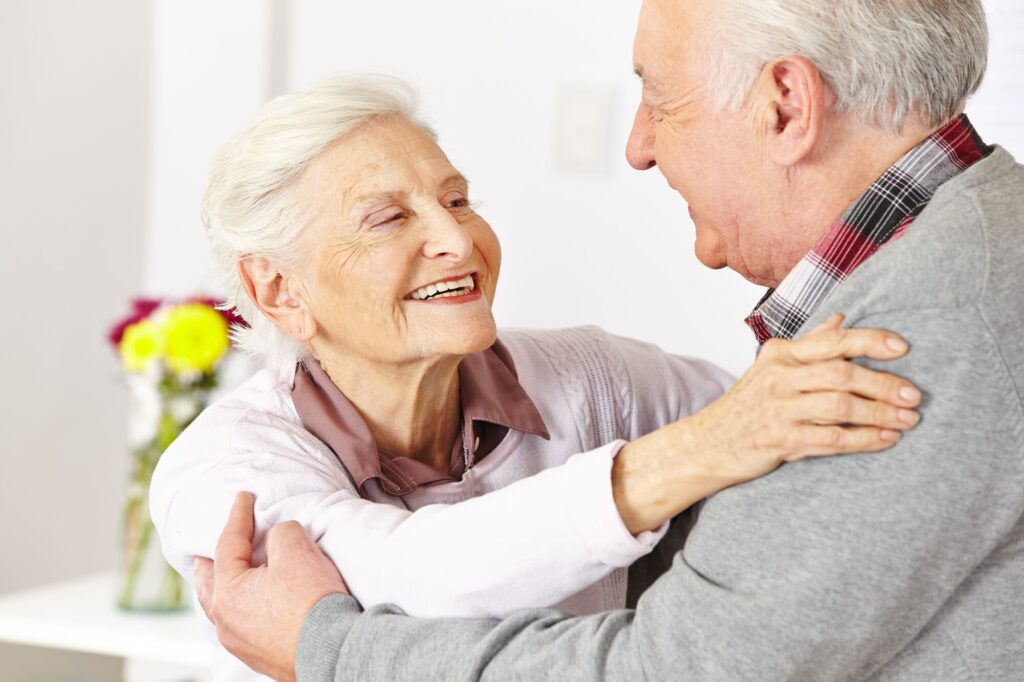 An elderly couple hugging each other