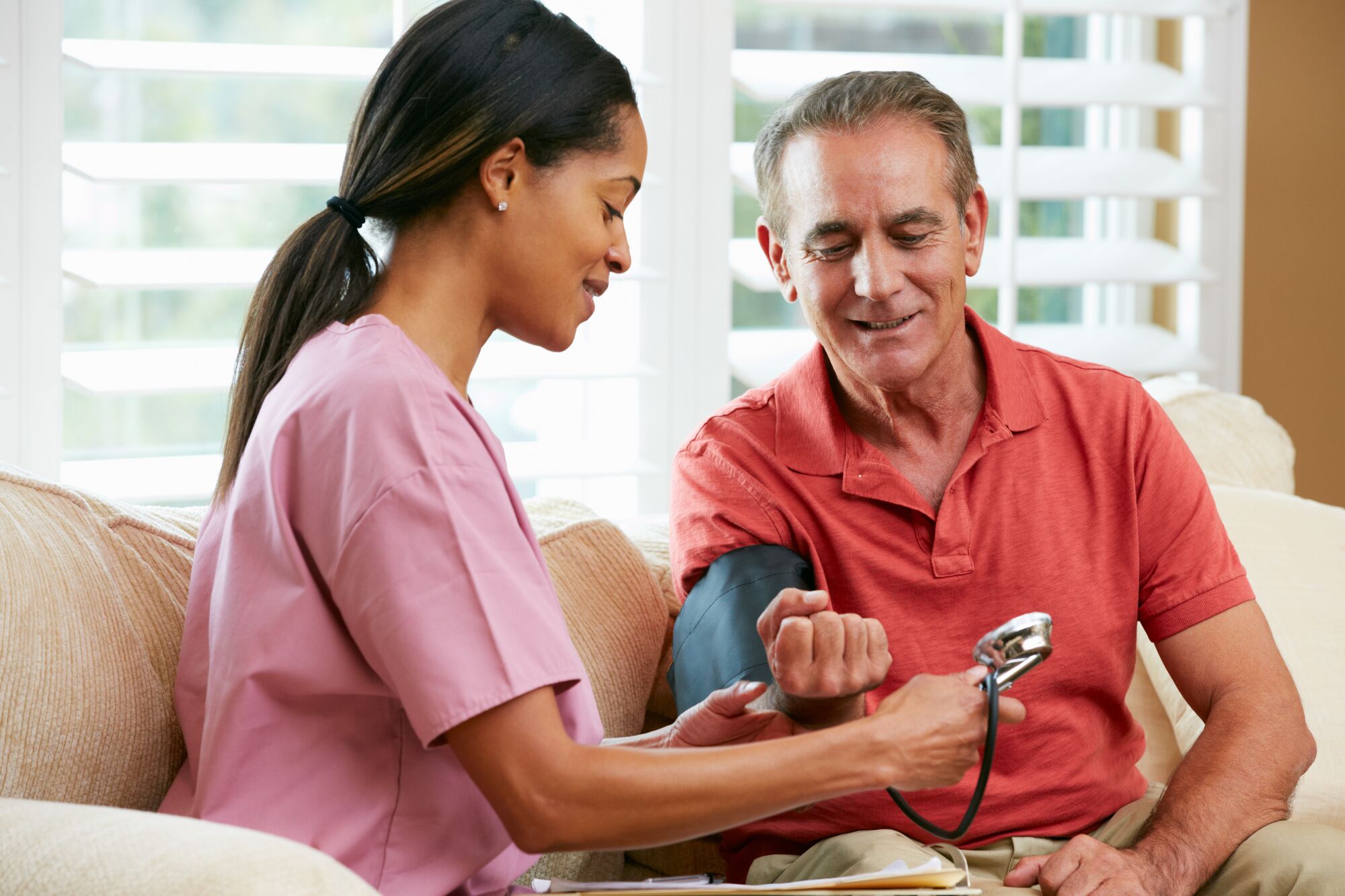Elderly man getting blood pressured measured by a care giver